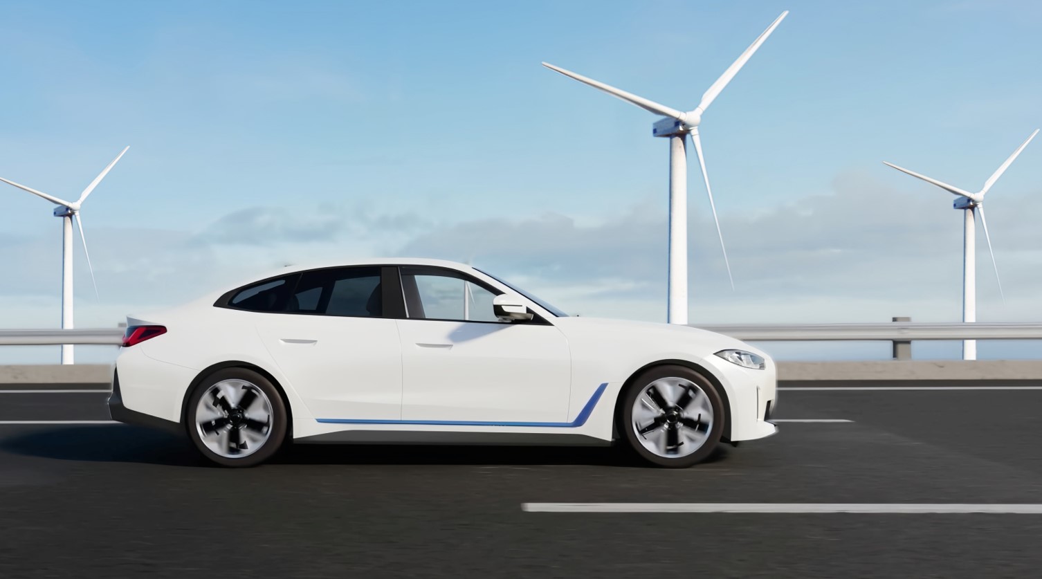 White car driving on a road with wind turbines in the background